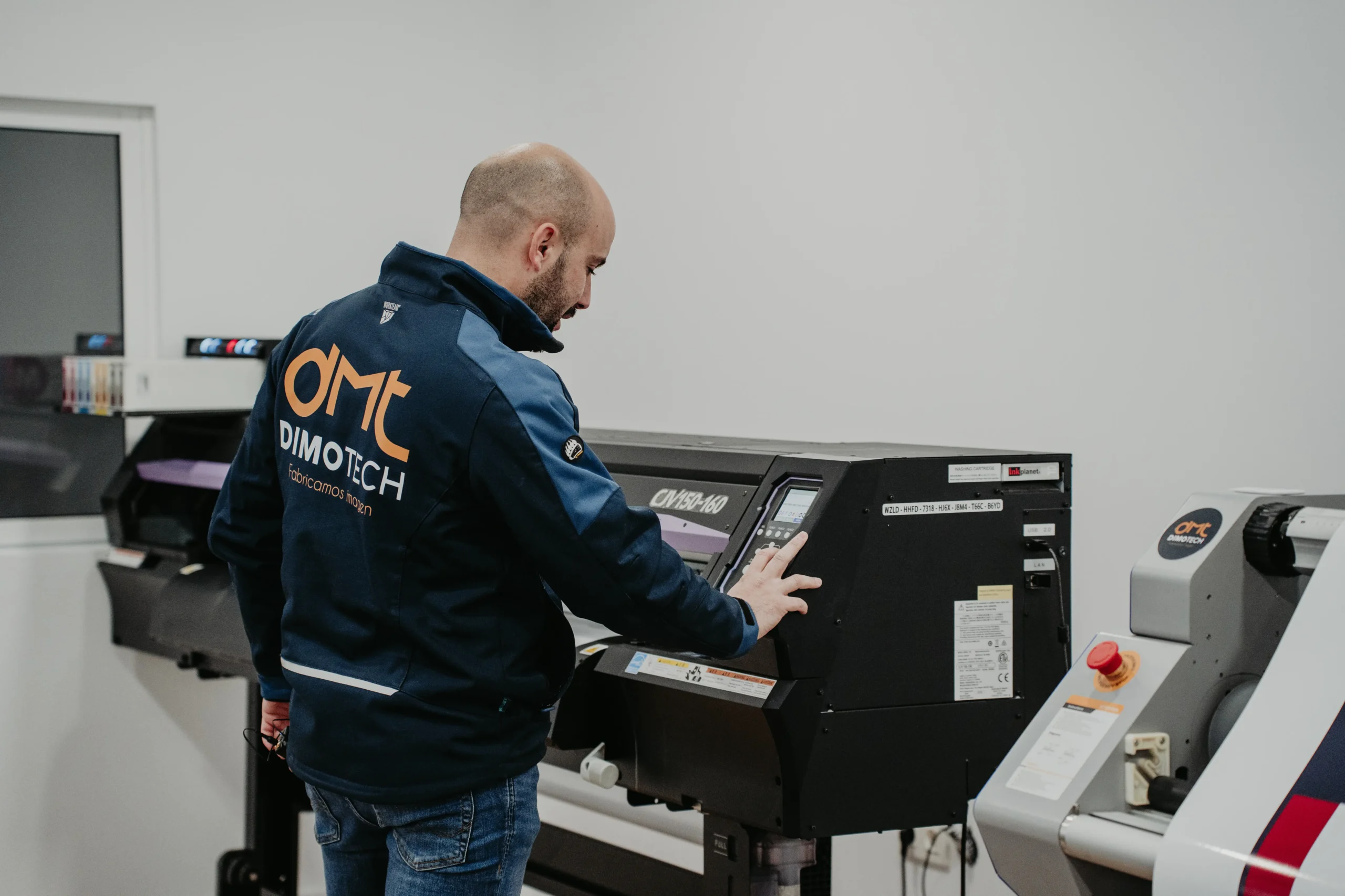 Técnico operando máquina ploter impresión gran formato para logos